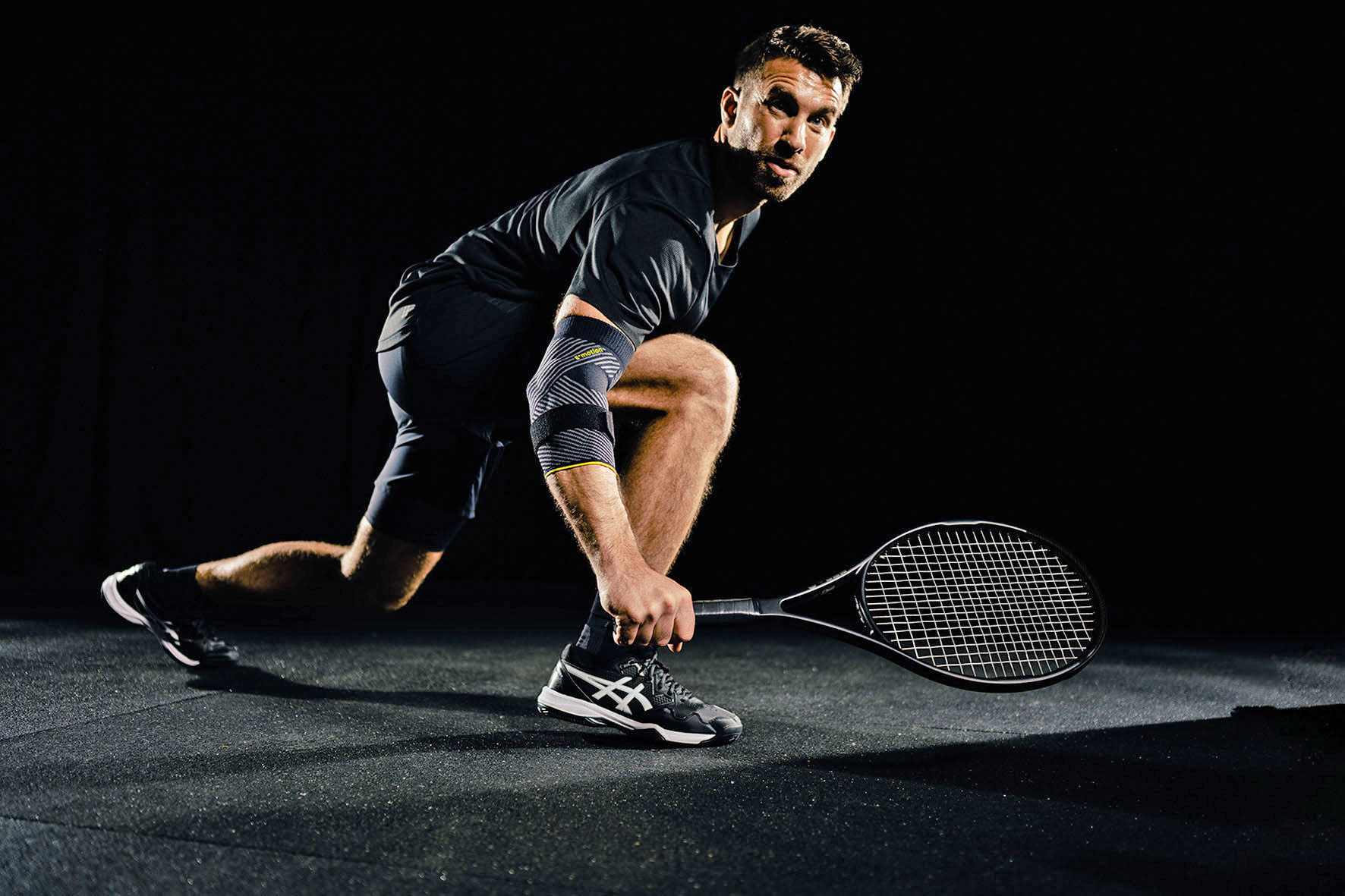 Mann mit Tennisschläger im Ausfallschritt