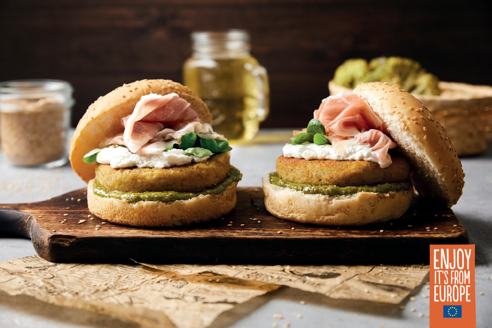 zwei Burger auf einem Holzbrettbelegt mit Pesto, Gemüse-Patty, Ziegenkäse und Schicken